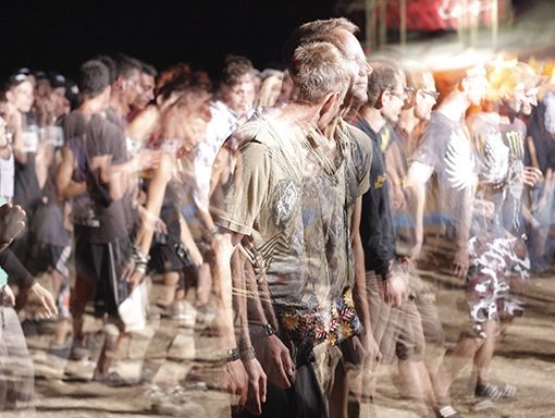 A dynamic crowd enjoys a vibrant night festival, with blurred motion capturing the event's energetic atmosphere.