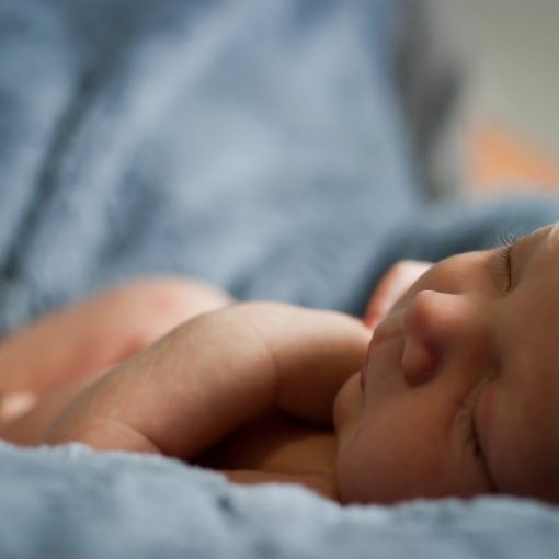 Close-up of a peaceful newborn baby sleeping on a soft blue blanket, highlighting tranquility and comfort.
