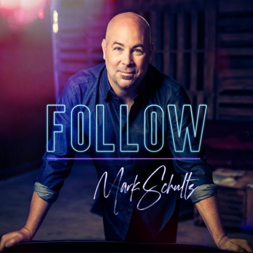 A person in a denim shirt with text FOLLOW overlayed in a dimly lit room, creative ambiance.
