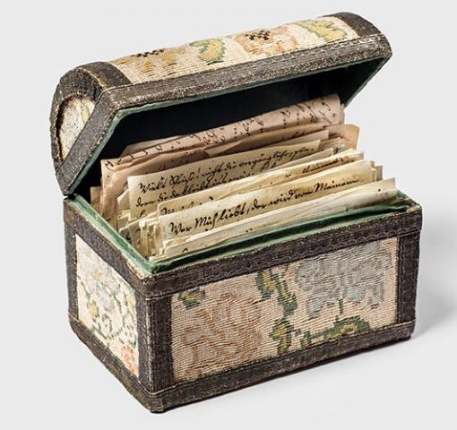 Decorative box with vintage letters, floral design, lid open, showcasing handwritten documents inside.