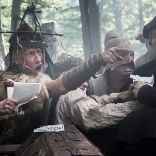 People in medieval costumes engaged in an intense dispute in a forest setting.