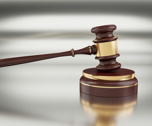 Wooden judge gavel on a shiny surface, symbolizing justice and legal authority in a courtroom setting.