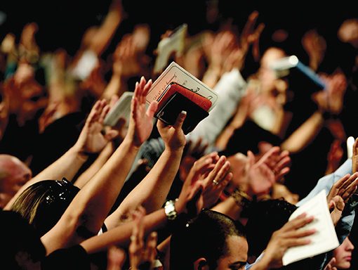 A crowd of people raising hands, holding books, in a vibrant gathering or event.