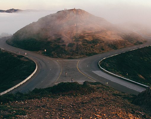 Curved roads meet at foggy mountain, creating a scenic view.