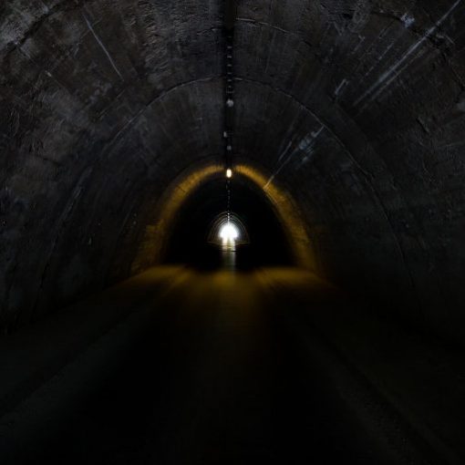 Dark tunnel interior with a bright light at the exit, symbolizing hope and new beginnings.