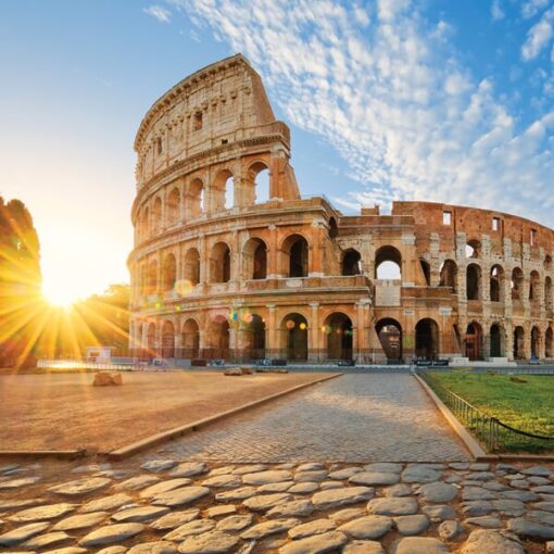 The Colosseum in Rome at sunrise, showcasing its ancient architecture against a vibrant blue sky.