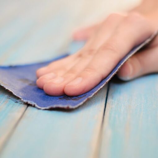 Hand sanding wooden surface with sandpaper for smooth finish.