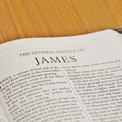 Open Bible displaying the General Epistle of James, focused on scripture text, wooden surface background.