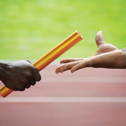 Close-up of a relay race baton handoff between two runners against a blurred track background.